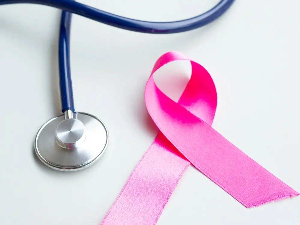 Estetoscópio ao lado de laço rosa, símbolo da campanha Outubro Rosa de prevenção ao câncer de mama.