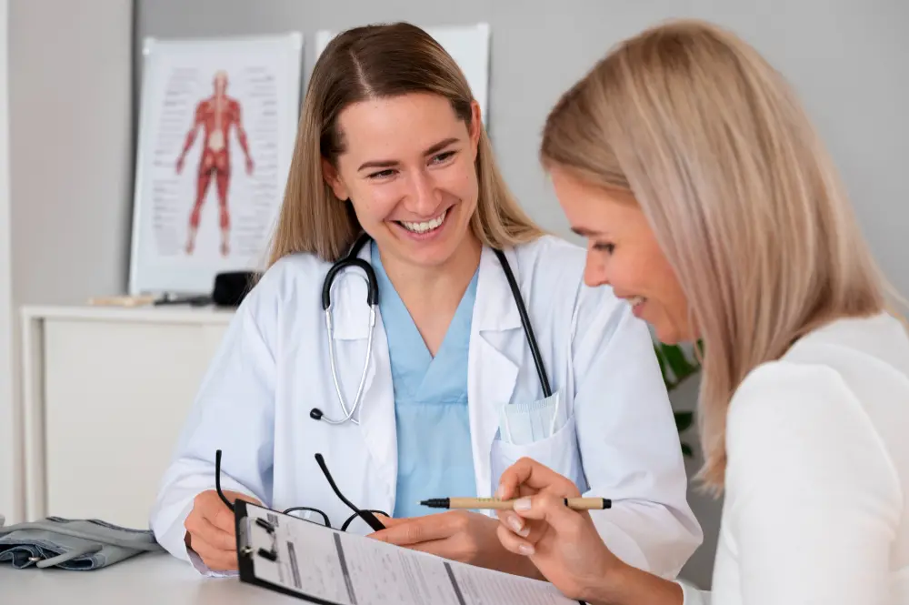 Médica sorridente conversa com paciente enquanto preenchem um formulário durante a consulta.